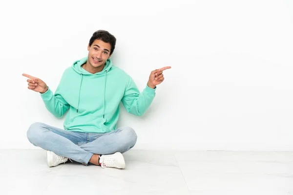 Caucasian Handsome Man Sitting Floor Pointing Finger Laterals Happy — Stockfoto