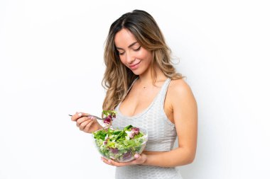 Beyaz arka planda izole edilmiş beyaz bir kadın elinde mutlu bir ifadeyle bir kase salata tutuyor.