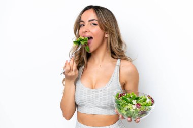 Beyaz arka planda izole edilmiş beyaz bir kadın elinde bir kase salata ile ona mutlu bir ifadeyle bakıyor.