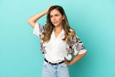 Soyutlanmış mavi arka planı olan genç bir kadın kafasını kaşırken şüpheye düşüyor.