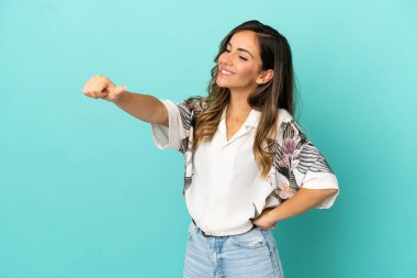 Soyutlanmış mavi arka planda genç bir kadın baş parmak işareti yapıyor.