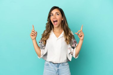 Izole mavi arka plan üzerinde genç kadın şaşırttı ve işaret