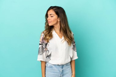 Soyutlanmış mavi arka planda genç bir kadın şüpheli hareketler yapıyor.