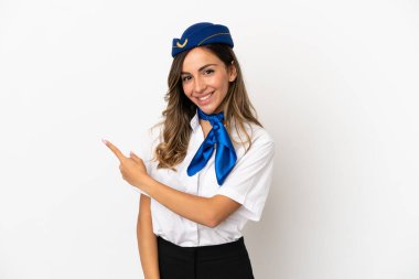 İzole edilmiş beyaz arka planda uçak hostesi bir ürünü sunmak için kenarı işaret ediyor.