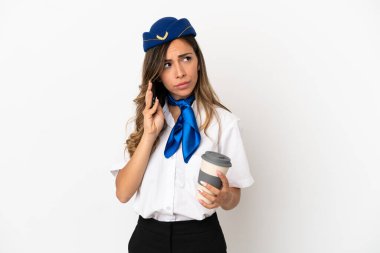 İzole edilmiş beyaz arka planda uçak hostesi elinde kahve ve cep telefonu var.