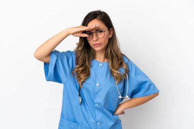 Genç cerrah kadın, izole edilmiş beyaz bir duvarın üzerinde elini uzatıp bir şeye bakıyor.