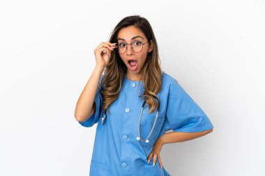 Genç cerrah kadın, gözlüklü ve şaşırmış bir şekilde izole edilmiş beyaz bir duvar.