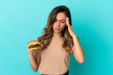 Elinde burgerle gezen genç bir kadın. Baş ağrısı var.