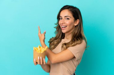 İzole edilmiş arka planda patates kızartması tutan genç bir kadın.