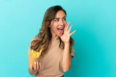 Arka planda kızarmış cips tutan genç bir kadın ağzı sonuna kadar açık bağırıyor.