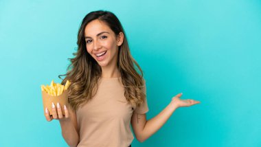 Kızarmış cipsleri izole edilmiş arka planda tutan genç bir kadın. Davet edilmek için ellerini yana uzatıyor.