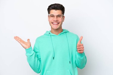 Beyaz fırında izole edilmiş genç beyaz beyaz bir adam. Avucunda hayali bir şey tutuyor. Bir ilan vermek için.