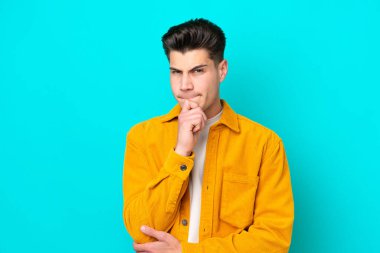 Young handsome caucasian man isolated on blue bakcground having doubts and thinking