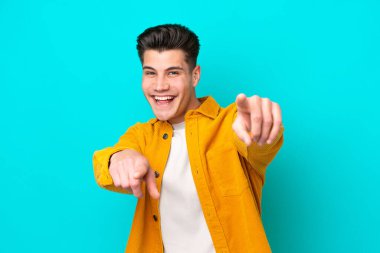 Genç, yakışıklı, beyaz bir adam mavi fırında izole edilmiş, mutlu bir ifadeyle ön tarafı işaret ediyor.