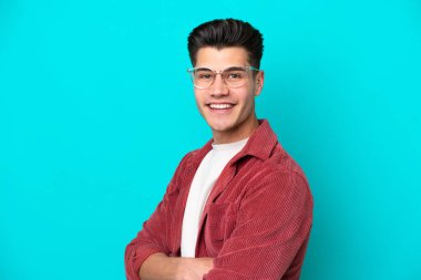 Genç, yakışıklı, beyaz bir adam mavi fırında tek başına, mutlu bir ifadeyle gözlüklü.