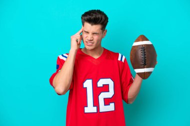 Rugby oynayan beyaz bir adam mavi arka planda baş ağrısıyla izole edilmiş.