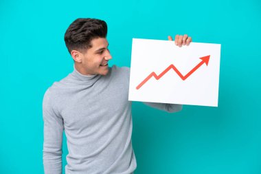 Mavi bakkalda izole edilmiş yakışıklı beyaz bir adam elinde mutlu bir ifadeyle büyüyen istatistik okunun sembolü olan bir tabela tutuyor.