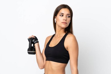 Beyaz arka planda izole edilmiş genç bir kadın halter olarak ağırlık kaldırıyor.