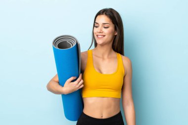 Minderli genç bir kadın mavi arka planda mutlu bir ifadeyle izole edilmiş.