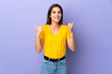 Kafkasyalı genç bir kadın soyutlanmış bir geçmişi var. Başparmakları havada ve gülümsüyor.