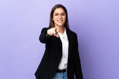 Mor arka planda izole edilmiş iş kadını kendine güvenen bir ifadeyle sana işaret ediyor.