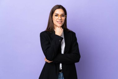 Mor arka planda gözlüklü ve gülümseyen bir iş kadını.