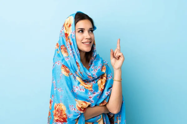 Young Moroccan woman with traditional costume isolated on blue background pointing up a great idea