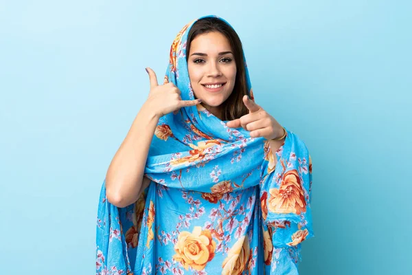 青の背景に隔離された伝統的な衣装を持つ若いモロッコの女性は電話ジェスチャーを作り 前を指す — ストック写真