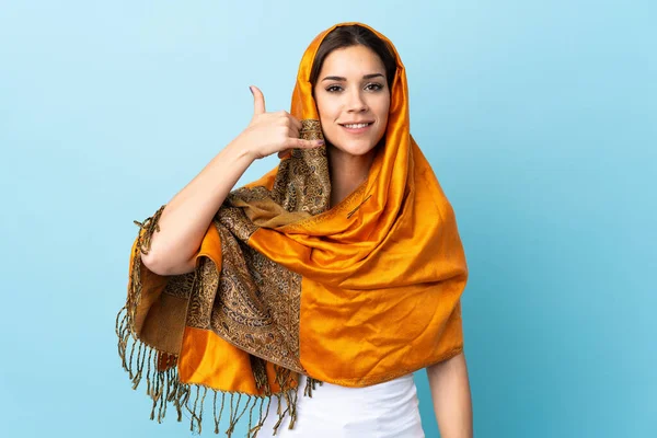 Young Moroccan woman with traditional costume isolated on blue background making phone gesture. Call me back sign