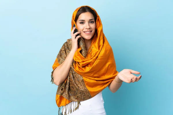 Молода Марокканка Традиційним Одягом Ізольована Синьому Фоні Розмовляє Кимось Мобільному — стокове фото