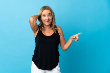 Orta yaşlı, soyutlanmış, şaşırmış ve işaret eden sarışın bir kadın.