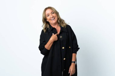 Orta yaşlı sarışın kadın, soyutlanmış beyaz bir arka plan ve şaşırtıcı bir yüz ifadesi var.