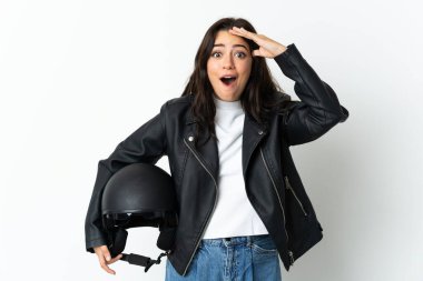 Beyaz arka planda motosiklet kaskı tutan bir kadın. Sürpriz bir ifadeyle.