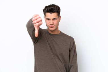 Beyaz bakkalda izole edilmiş genç, yakışıklı beyaz bir adam, olumsuz bir ifadeyle baş parmağını aşağı gösteriyor.