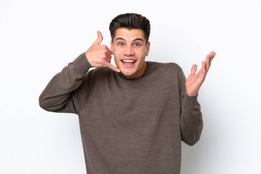 Beyaz fırında izole edilmiş yakışıklı beyaz bir adam telefon jesti yapıyor ve kuşkulanıyor.