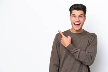 Beyaz fırında izole edilmiş yakışıklı beyaz adam şaşırmış ve işaret ediyor.