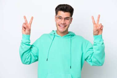 Beyaz bakkalda izole edilmiş yakışıklı beyaz adam zafer işareti gösteriyor.