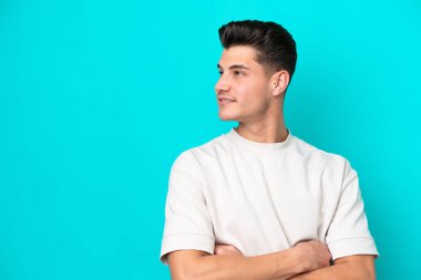 Genç, yakışıklı, beyaz bir adam, mavi bir bakkalda izole edilmiş, yan tarafa bakıyor.