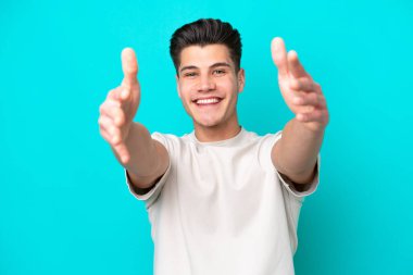 Genç, yakışıklı, beyaz bir adam, mavi bir bakkal bahçesinde izole edilmiş.