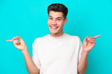 Genç, yakışıklı, beyaz bir adam, mavi bir bakkalda izole edilmiş, parmak uçlarında ve mutlu.