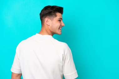 Genç, yakışıklı, beyaz bir adam mavi bir bakkalda izole edilmiş.