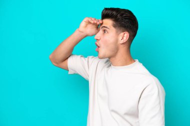 Genç, yakışıklı, beyaz bir adam, mavi bir fırında tek başına, bakınırken yüzünde sürpriz bir ifade var.