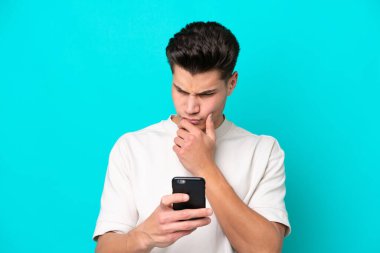 Genç, yakışıklı, beyaz bir adam, mavi bir bakkalda izole edilmiş. Düşünüyor ve mesaj yolluyor.