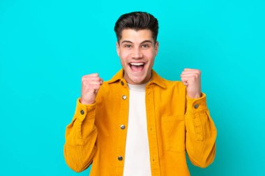 Genç, yakışıklı, beyaz bir adam mavi bir bakkalda tek başına zaferi kutluyor.