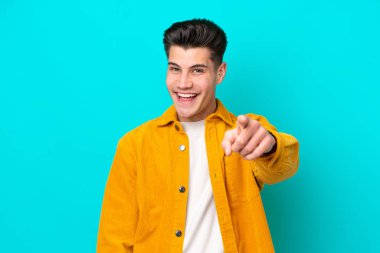 Genç, yakışıklı, beyaz bir adam mavi fırında izole edilmiş, şaşırmış ve ön tarafı işaret ediyor.