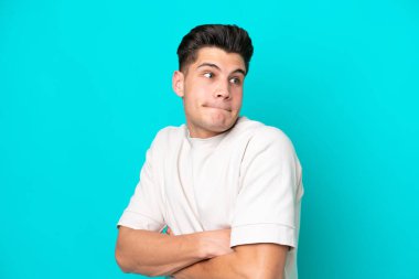 Genç, yakışıklı, beyaz bir adam, mavi fırında tek başına, omuzlarını kaldırırken şüpheyle hareket ediyor.