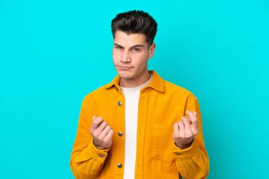 Genç, yakışıklı, beyaz bir adam, mavi bir bakkalda izole edilmiş, para jesti yapıyor ama mahvolmuş.