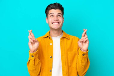 Genç, yakışıklı, beyaz bir adam, mavi fırında izole edilmiş, parmaklarını çapraz yapıp, en iyisini diliyor.