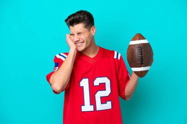 Rugby oynayan genç beyaz adam mavi arka planda izole edilmiş hayal kırıklığına uğramış ve kulaklarını kapatmış.