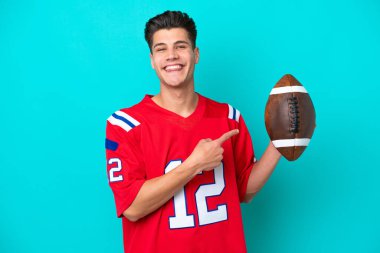 Rugby oynayan beyaz bir adam mavi arka planda izole edilmiş.